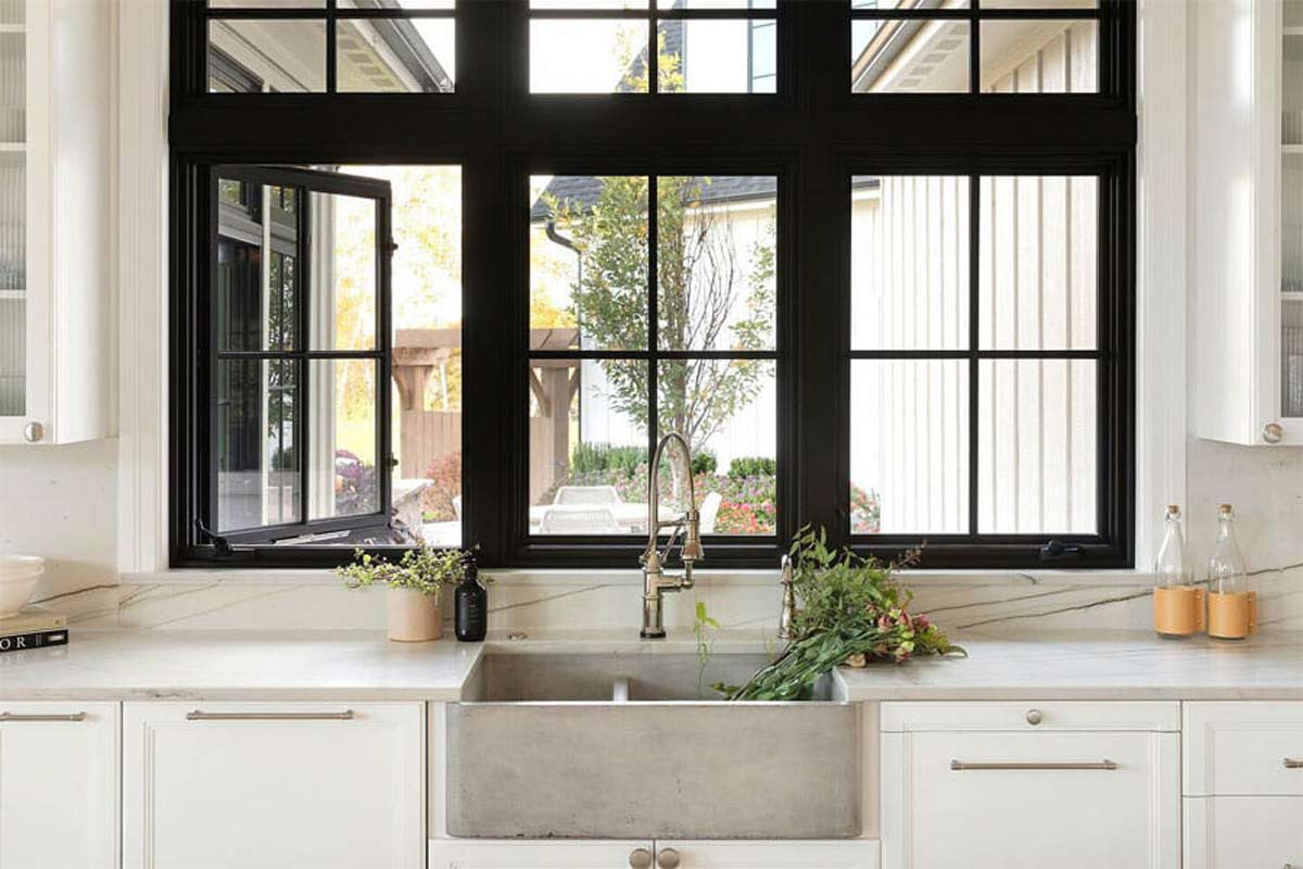 Black Andersen casement windows above a white farmhouse kitchen sink