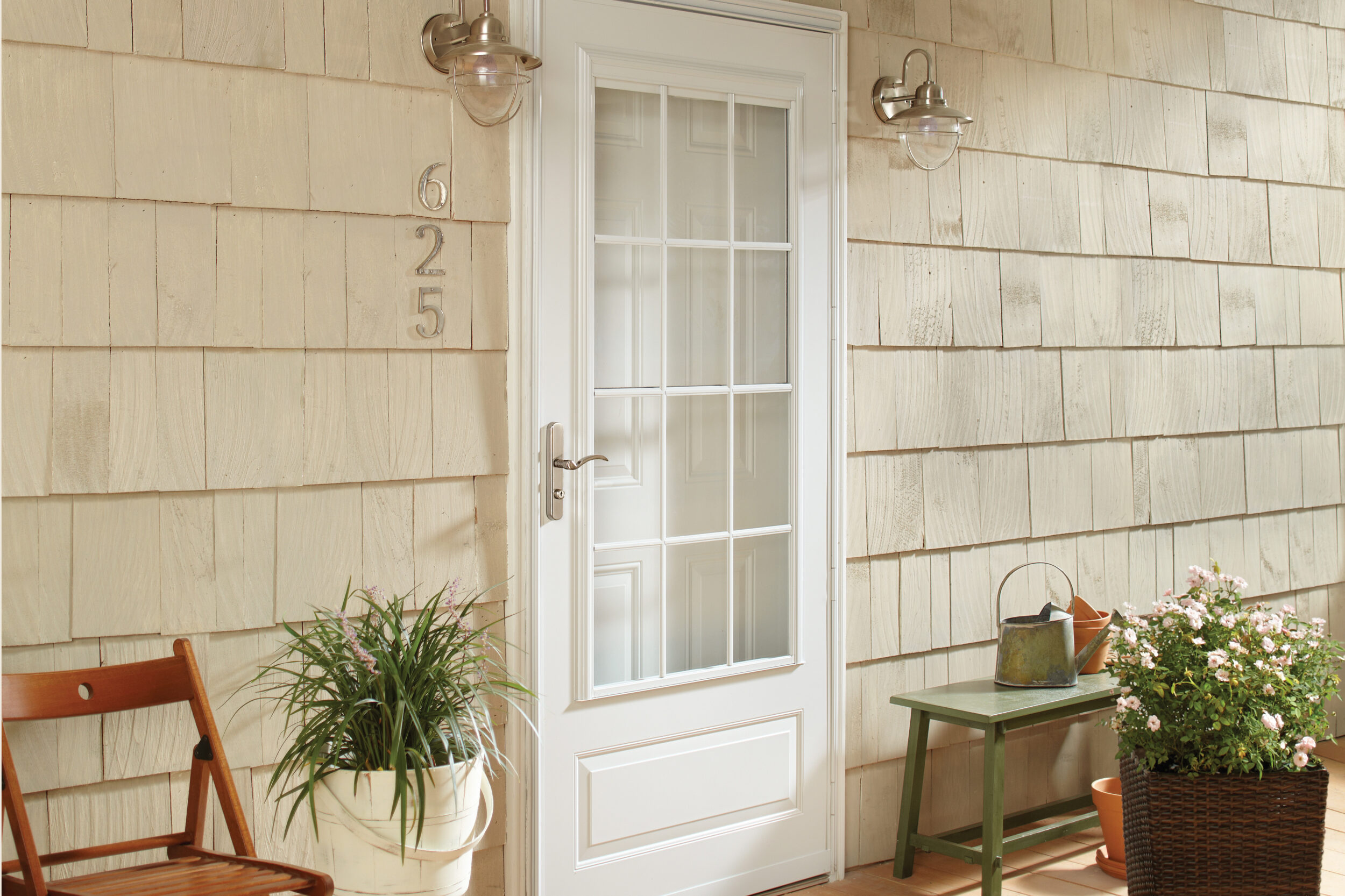 White Andersen storm door on a welcoming cedar-shingle porch with flowering plants