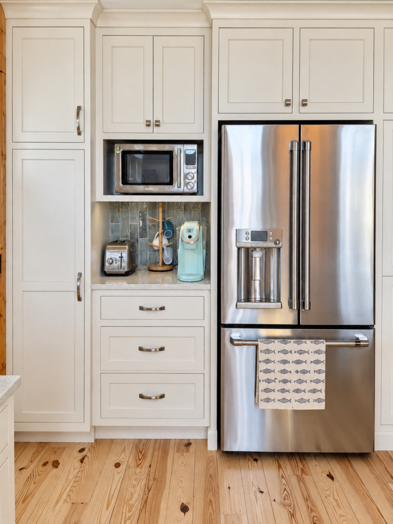 Cream pantry and coffee station cabinetry surrounding a stainless steel refrigerator.
