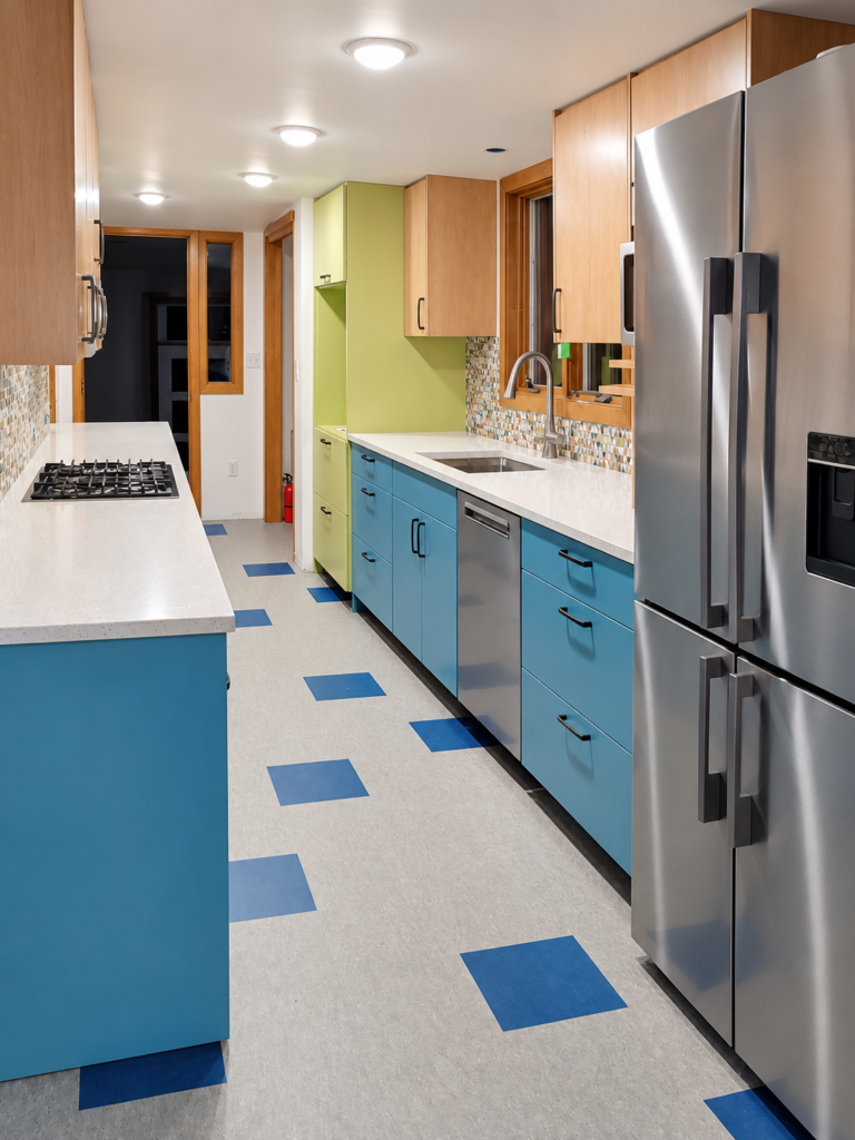 Narrow galley kitchen with blue cabinets, wood uppers, a gas cooktop and stainless steel refrigerator.