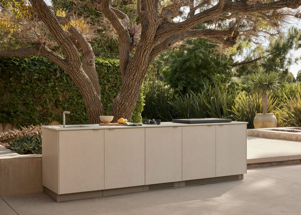 Dekton outdoor kitchen and dining area beneath a large tree, by Cosentino