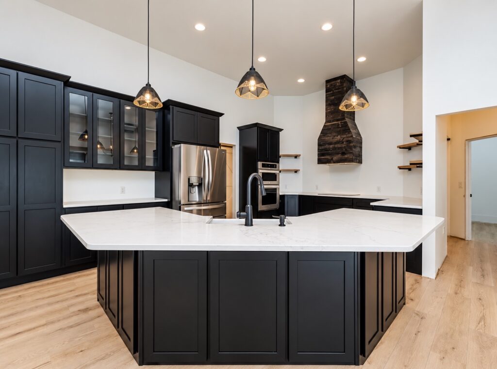 Dark paneled kitchen island with white countertops, a black faucet, stainless appliances and three pendant lights.